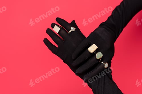 Preview: cropped view of female hands in black gloves with rings isolated on red