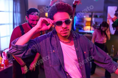 Preview: Young Hispanic Man Wearing Sunglasses Dancing at House Party Indoors