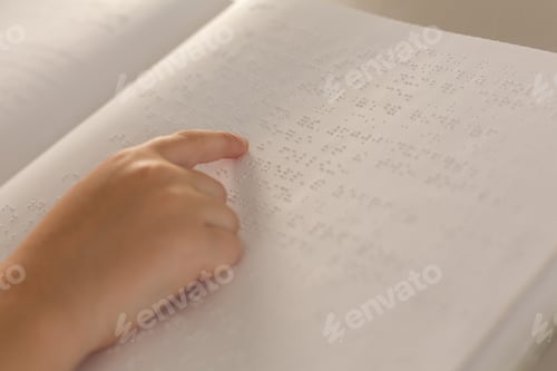 Preview: Close-up of a blind boy hand reading a braille book in classroom at elementary school