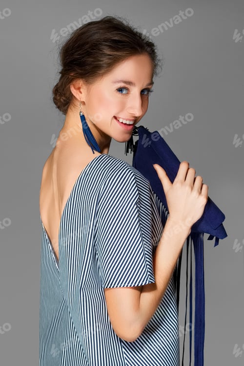 Preview: attractive lady in dress in stripes posing in studio with bag