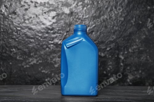 Preview: Motor oil in blue canister on black table near dark wall