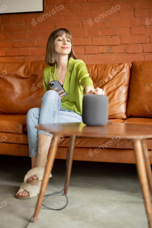 Preview: Woman touching smart speaker while sitting on couch at home