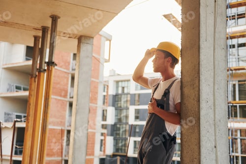 Preview: Resting indoors. Young man working in uniform at construction at daytime