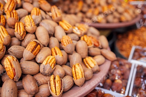 Preview: Pile of fresh pecans in their shells displayed on a market table