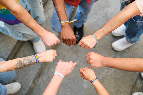 Preview: A group of multiracial people with rainbow LGBTQ bracelets standing in a circle.