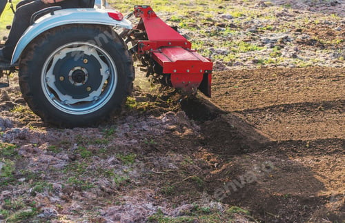 Preview: Tractor cultivating soil in the garden. Selective focus.