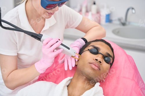 Preview: Aesthetician carrying out hair removal on young man face