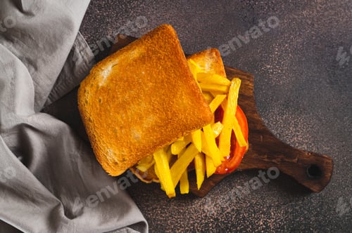 Preview: Close up of fried toasts with french fries and tomato on a board on the table top view