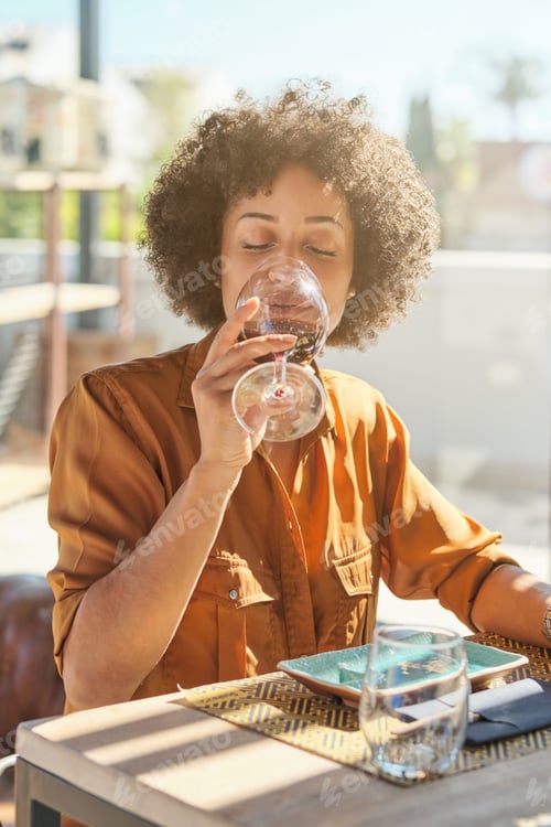 Preview: Young African American female drinking red wine in sushi restaur