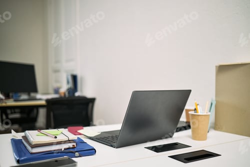 Preview: Empty Office Desk with Laptop and Supplies Awaiting Cleaning Staff Arrival