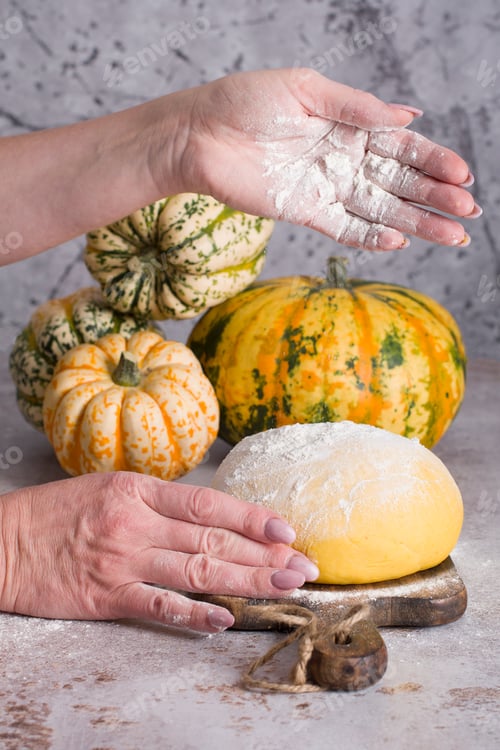 Preview: Female hands kneading dough for cinnabons on a background of pumpkins