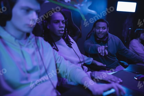Preview: Excited indian man pointing with finger near interracial friends in computer club