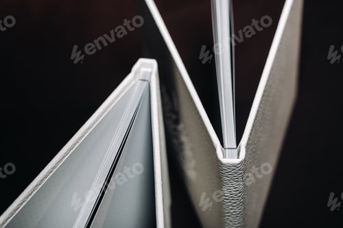 Preview: Composition of photo books in natural white leather of different sizes. The white paper on a dark