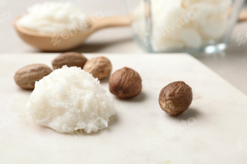 Preview: Shea butter and nuts on marble board, closeup. Space for text