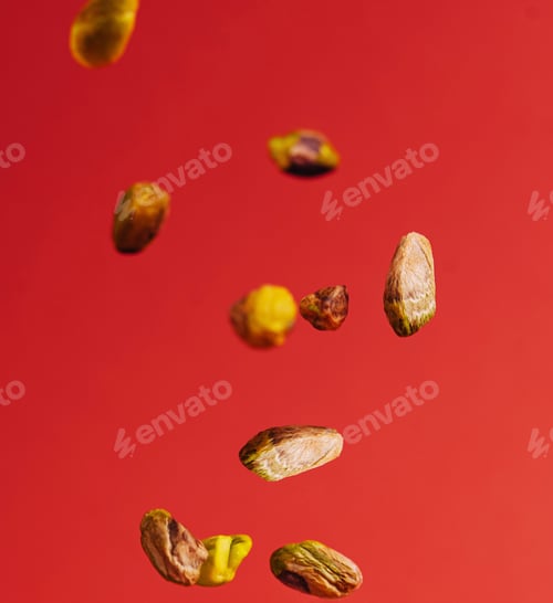 Preview: Pistachios falling down on red background