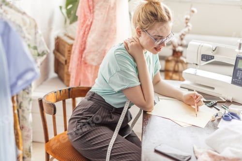 Preview: Fashion designer at work. Talanted dressmaker drawing sketch at her workspace