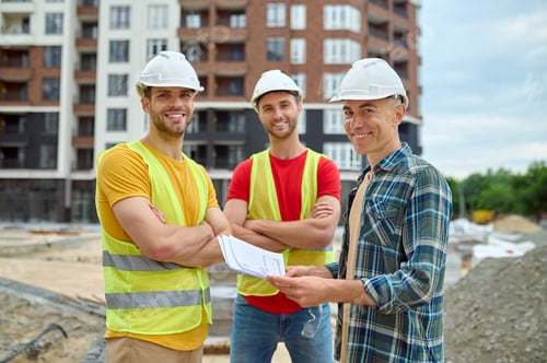 Preview: Engineer with drawing and two workers at construction site