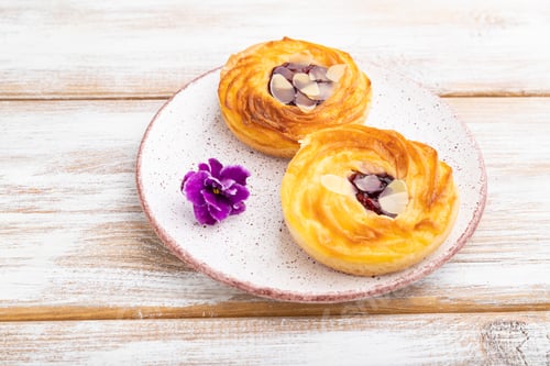 Preview: Small cheesecakes with jam and almonds on white wooden background. Side view.