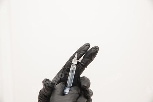Preview: A close-up photo of doctors in disposable latex rubber gloves holding a syringe shows the injection