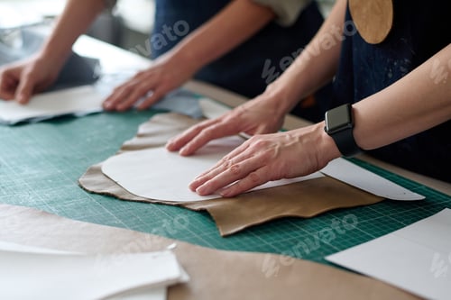 Preview: Close-up of hands of two female tailors or tanners with sewing patterns
