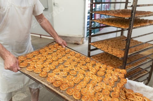 Preview: The baker places the fresh salted pretzels taken out of the oven.Trays with many pretzels