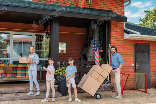 Preview: parents with cardboard boxes and children standing at country house, moving home concept
