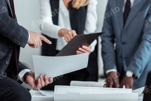 Preview: cropped view of businesswoman holding clipboard near multicultural partners