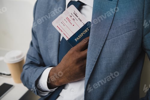 Preview: Cropped image of African american man hiding passport and fly ticket into pocket in suit