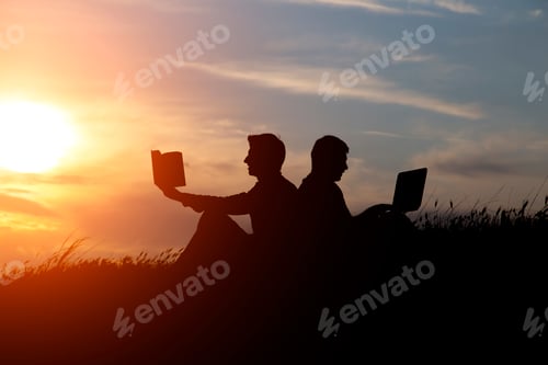 Preview: silhouette of a men with laptop and a book on sunset or sunrise background