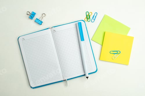 Preview: Overhead view of open blue notebook and pen colorful note papers lying on white background