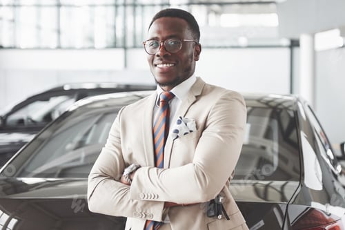 Preview: Young black businessman on auto salon background. Car sale and rent concept