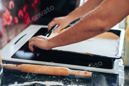 Preview: Man makes pizza at home in the kitchen. Places the dough on baking sheet