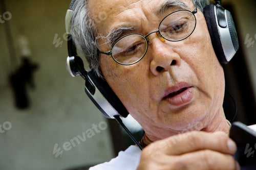 Preview: Senior man relaxing at home reading E-book on his tablet.