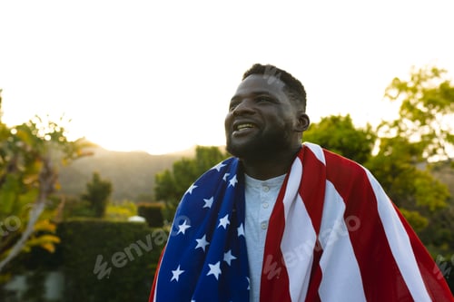 Preview: Happy african american man with flag on back american flag in sunny garden