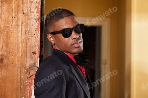 Preview: Retro Fashion Afro American Groom Wearing Black Suit And Tie And Sunglasses. Interior Of Old House.