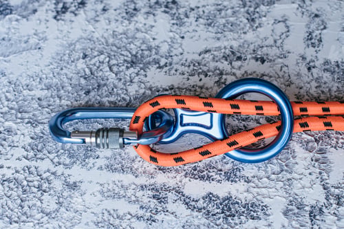 Preview: Isolated photo of climbing equipment. Part of carabiner lying on the white and grey colored surface