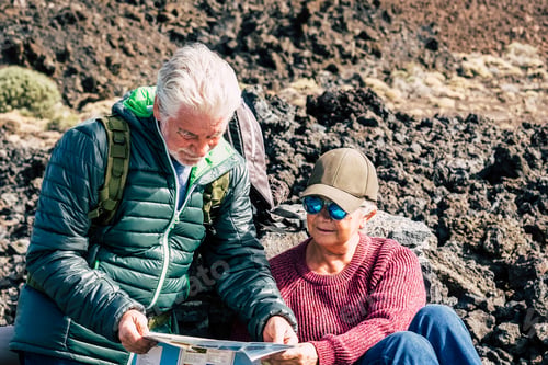 Preview: Active traveler senior couple check the map in trekking excursion together - healthy mature