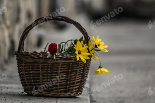 Preview: Closeup shot of a rose and yellow daisies in the basket on a stone surface