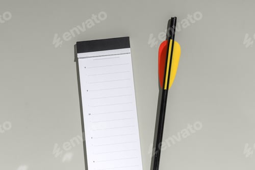 Preview: Blank daily planner lies beside black arrow on gray background, minimalist concept for goals