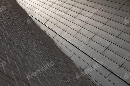Preview: Wide angle view of junction of grey paving flag walkway and grey metal wall