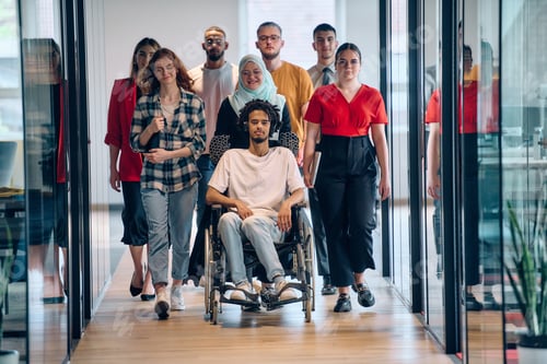 Preview: A diverse group of young business people congregates within a modern startup's glass-enclosed office