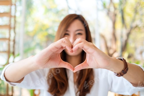 Preview: A beautiful asian woman making heart hand sign with feeling happy