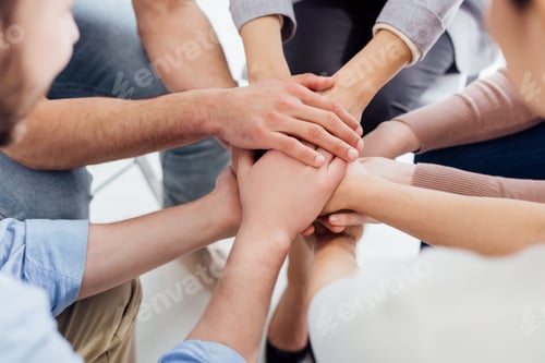 Preview: cropped view of people stacking hands during group therapy session