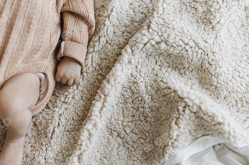 Preview: Close up of cute newborn baby hand and fingers while sleeping on cozy blanket