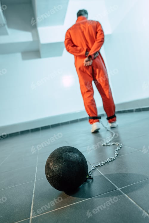 Preview: rear view of prisoner in orange uniform with weight tethered to leg