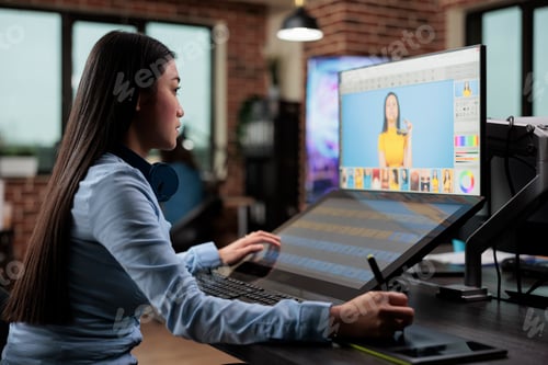 Preview: Creative agency asian employee retouching digital photos while using touchscreen display and stylus
