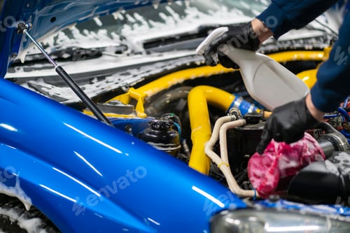 Preview: a male detailer with brush cleaning the engine bay