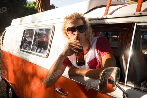 Preview: Man drinking beer while leaning on camper van window