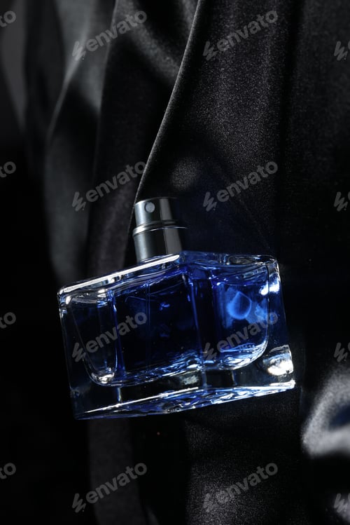 Preview: Luxury men's perfume in bottle on black satin fabric, top view