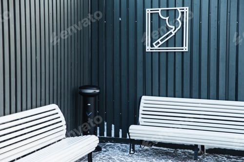 Preview: Smoking area with ash bin and two white benches for relaxation. Sign on cigarette on fence